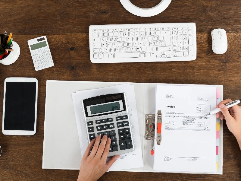 A person using a calculator on top of papers.